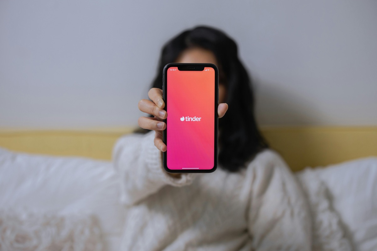 Person holding a phone showing the Tinder app